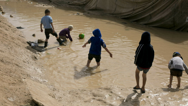 Children play in a mud puddle in the section for foreign families at Al-Hol camp in Hasakeh province, Syria. 