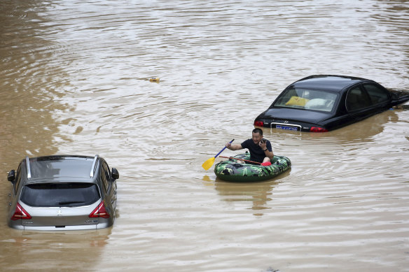 A man paddles past submerged cars during a flood in Rongshui County in southern China's Guangxi Zhuang Autonomous Region.
