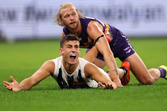 Nick Daicos of the Magpies looks to the umpire after marking the ball against Corey Wagner of the Dockers.