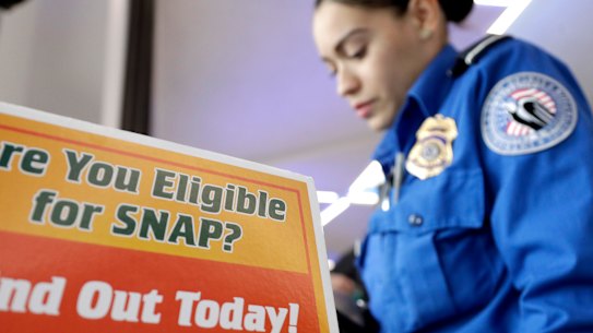 A Transportation Security Administration employee stands at a booth to learn about a food stamp program at Newark Liberty International Airport, which has been affected by the government shutdown. 