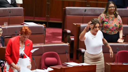 Lidia Thorpe appears to throw papers towards Pauline Hanson, with Fatima Payman (back left) seated behind them.