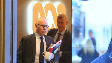 The ABC's executive editor John Lyons is followed by an AFP officer during Wednesday's raids.