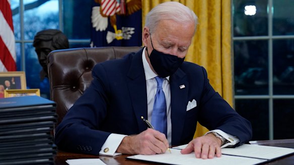 President Joe Biden signs his first executive orders in the Oval Office of the White House.