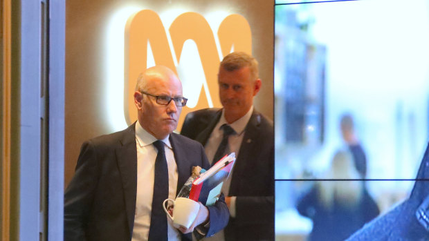 The ABC's executive editor John Lyons is followed by an AFP officer during Wednesday's raids.
