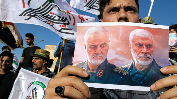 A supporter of an Iran-backed militia holds a poster of slain Iranian General Qassem Soleimani, left, and deputy commander Abu Mahdi al-Muhandis during a protest by pro-Iranian militiamen in Iraq last year.