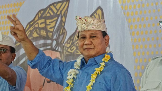 Prabowo Subianto pictured at an event in Bali waving a 'V' for victory sign,  or maybe '2', his ballot number, to his volunteers.