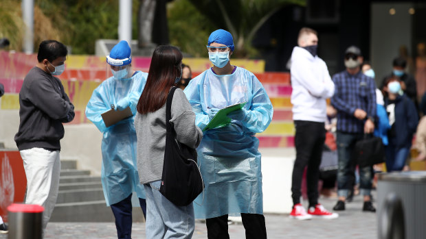 Nurses speak to people waiting in line at a testing station on High St, Auckland, near the A-Z Collection store where a worker has tested positive for COVID-19.