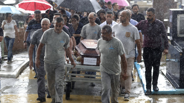Cemetery employees carry the coffin of Kaio Limeira, 15.