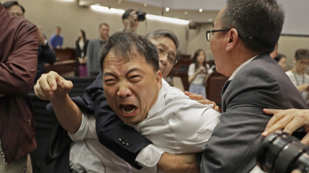 Pro-democracy lawmaker Wu Chi-wai, centre, is restrained by security guards at the Legislative Council in Hong Kong, on Saturday.