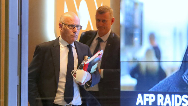 The ABC's executive editor John Lyons is followed by an AFP officer during Wednesday's raids.