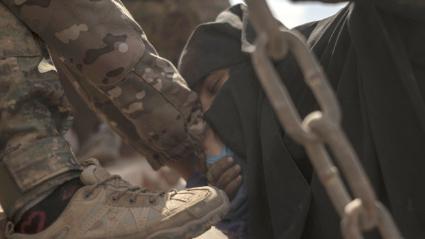 A woman kisses the hand of a soldier after leaving the IS stronghold.
