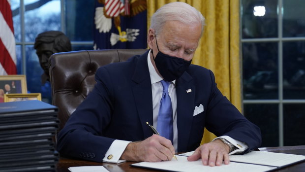President Joe Biden signs his first executive orders in the Oval Office of the White House.