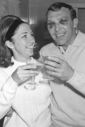 His face battered and blackened, Bobby Skilton joins his wife Marion in a champagne toast at their home after the Brownlow win.