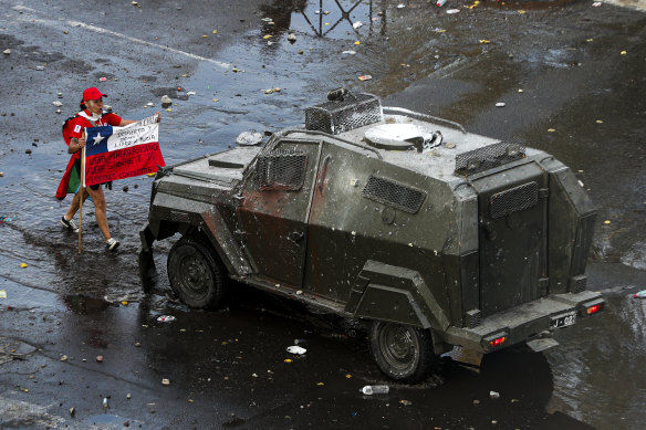 A demonstrator holds a Chilean flag toward an armored police vehicle Chile's capital, Santiago, this week.