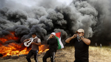 Palestinian protesters chant slogans next to burning tires during clashes with Israeli troops along Gaza's border with Israel, east of Khan Younis, Gaza Strip.