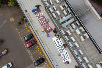 Banners are on the roof of the hotel, saying, "let them out".