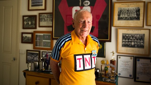 Noel Bissett wears his old referee uniform standing in front of his many awards that he has earned over the years. He has been inducted into the ACT Sport Hall of Fame as an associate member. 