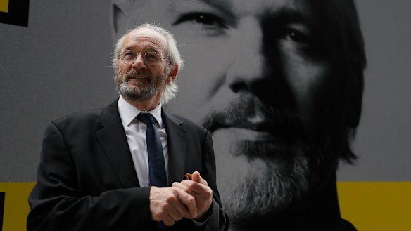 Julian Assange's biological father John Shipton stands in front of his poster near the Central Criminal Court Old Bailey in London, Tuesday.