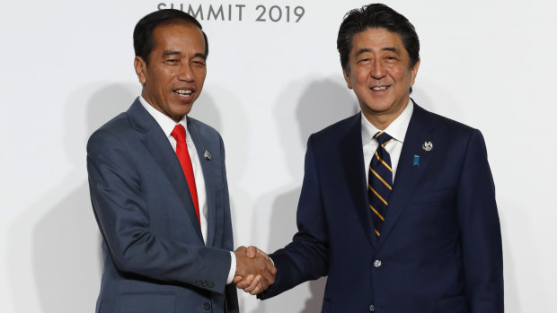 Getting on with it: Indonesian President Joko Widodo, left, is welcomed by Japanese Prime Minister Shinzo Abe in Osaka, a few hours after the court's decision confirming his election win.