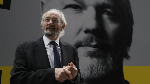 Julian Assange's biological father John Shipton stands in front of his poster near the Central Criminal Court Old Bailey in London, Tuesday.