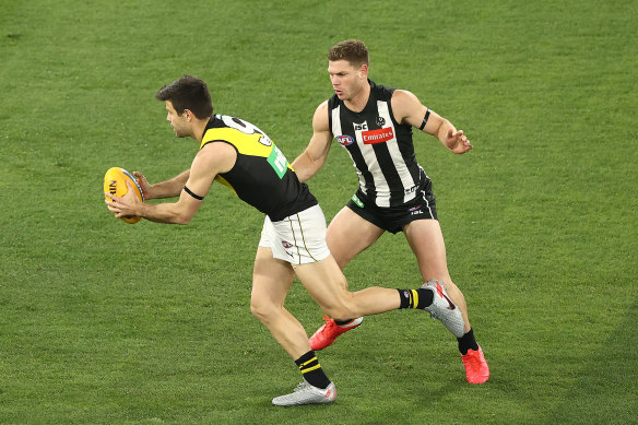 Trent Cotchin, left, runs with the ball during round two against Collingwood. 