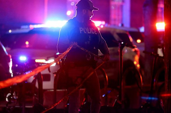 A police officer hangs yellow crime tape at the university.
