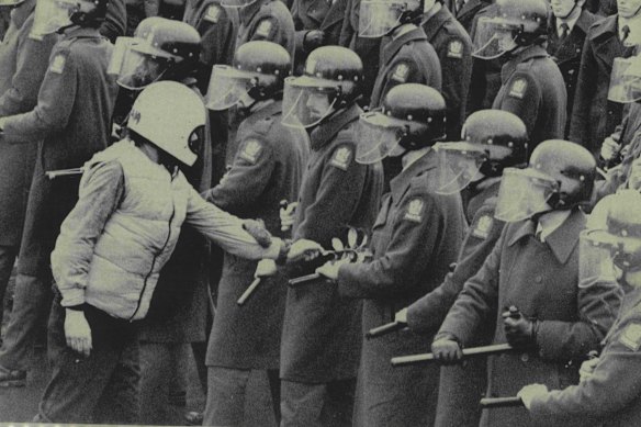 A protester lays an olive branch on the baton of a riot policeman outside Lancaster Park in Christchurch where the first Test between South Africa and New Zealand was being played in 1981.