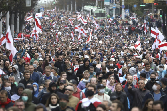 People carry old Belarusian national flags during a march to protest the official presidential election results.