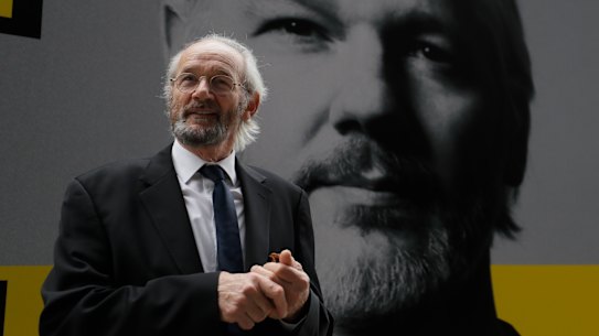 Julian Assange's biological father John Shipton stands in front of his poster near the Central Criminal Court Old Bailey in London, on Tuesday.