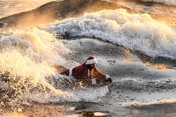 Carlos Hebert Plante, who boogie boards daily, dressed as Santa Claus hits the St-Lawrence River amid an air temperature of -14 degrees Celsius on Christmas Day, in Montreal.