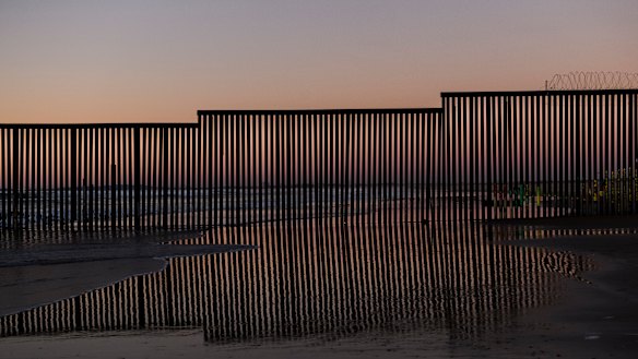 The border fence between San Diego, California, and Tijuana is reflected in a puddle of sea water as seen from Mexico.