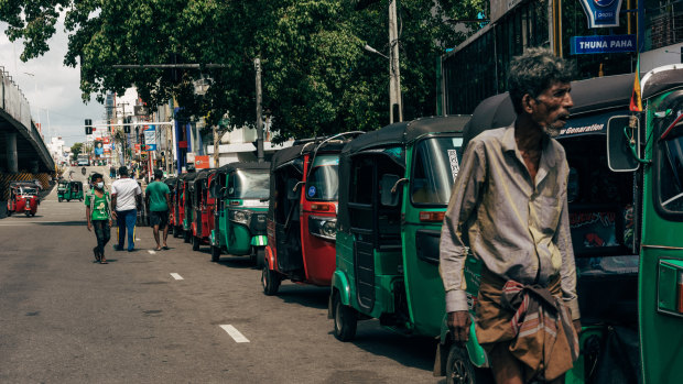 Three-wheeler vehicles queue for petrol in Colombo.