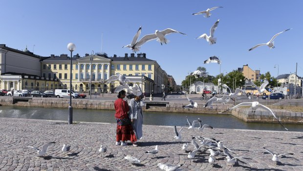 Tourists feed seagulls in front of the Presidential palace in Helsinki, Finland. The city will play host to a Trump-Putin meeting in July.