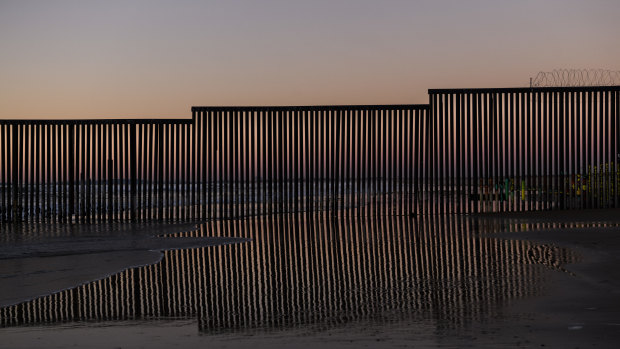 The border fence between San Diego, California, and Tijuana is reflected in a puddle of sea water as seen from Mexico.