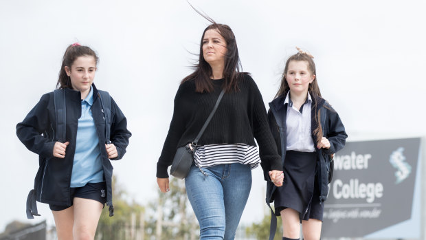 Casey Knight walks with children Stella and Matilda, who face another school move due to lack of funding.