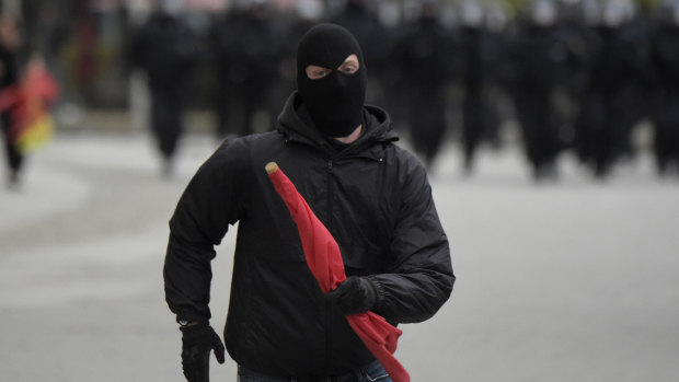A masked leftist demonstrator flees approaching police who try to separate leftist and nationalist demonstrators in Chemnitz, eastern Germany, on Saturday.