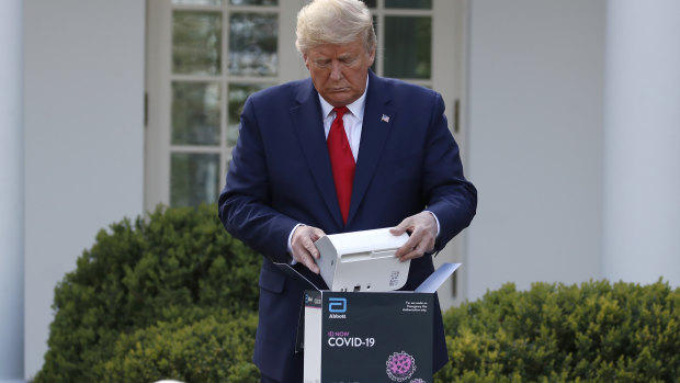 US President Donald Trump opens a box containing a 5-minute test for COVID-19 from Abbott Laboratories.