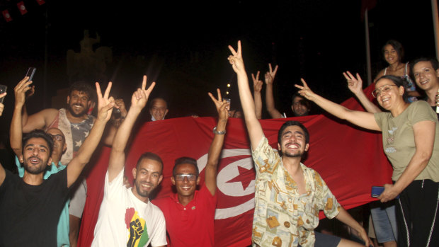 Demonstrators celebrate with a Tunisian national flag during a rally after the president suspended the legislature and fired the prime minister in Tunis, Tunisia.