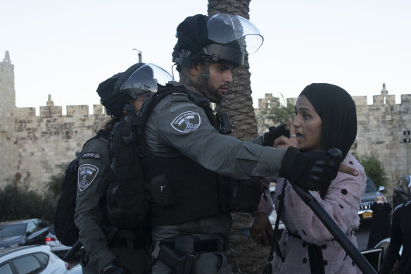 An Israeli border police officer faces off with a Palestinian woman at a protest at the Damascus Gate to the Old City of Jerusalem Thursday, June 17, 2021. 