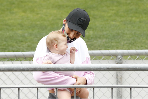 Netballer Kim Ravaillion, Treloar’s partner, with their daughter Georgie, watch on as Treloar has his picture taken.