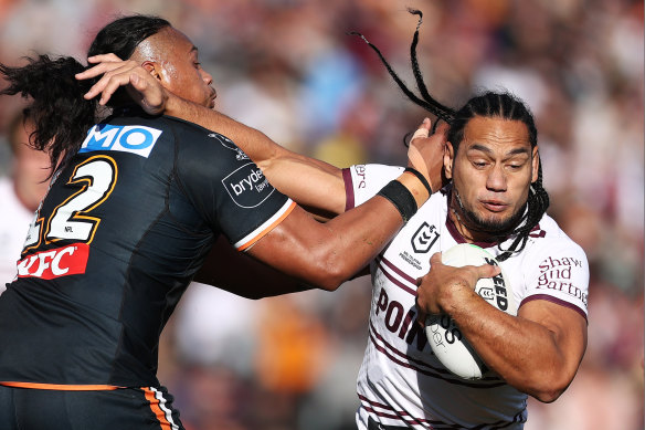 Martin Taupau fends off Luciano Leilua during Manly’s big win over Wests Tigers.