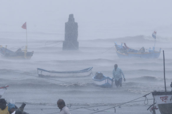 A fisherman waits for help as he tries to move a fishing boat to safer ground on the Arabian Sea coast in Mumbai on Monday.