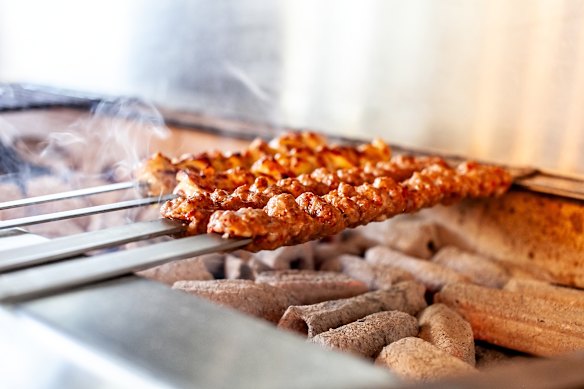 Espetos de carne grelhados em churrasqueira a carvão.