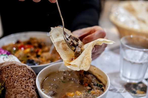 Enjoying alicha yebeg wat (lamb stew) with pita flatbread.