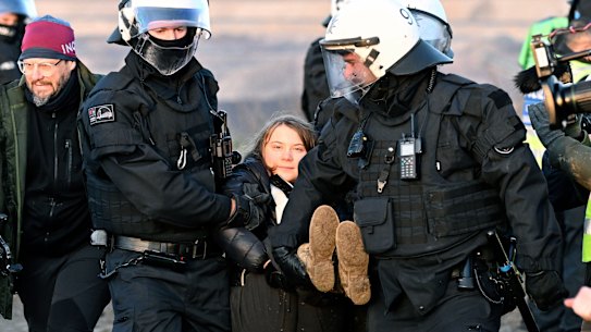 Police officers carry Swedish climate activist Greta Thunberg away.