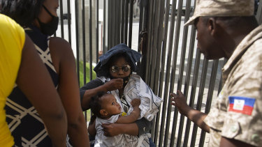 A Haitian police asks a woman to move away from a gate at the US Embassy in Port-au-Prince, Haiti.