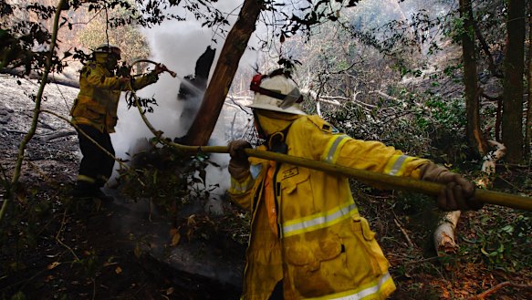 Kurrajong Heights firefighters work on  burnt-out bushland at Berambing on Monday ahead of ominous forecasts this week.