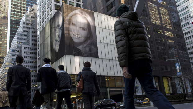 Pedestrians walk by photographs of Harry Macklowe and his new wife, Patricia Landeau, at 432 Park Ave., in New York. 