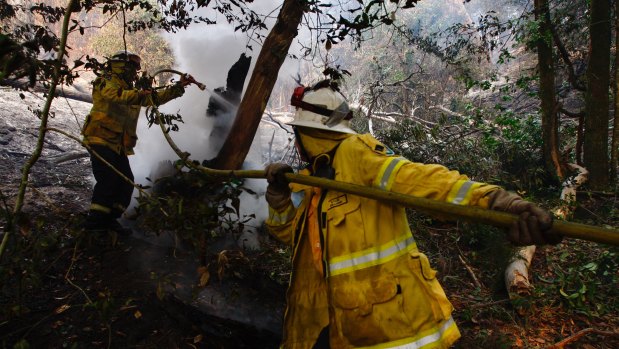 Kurrajong Heights firefighters work on  burnt-out bushland at Berambing on Monday ahead of ominous forecasts this week.