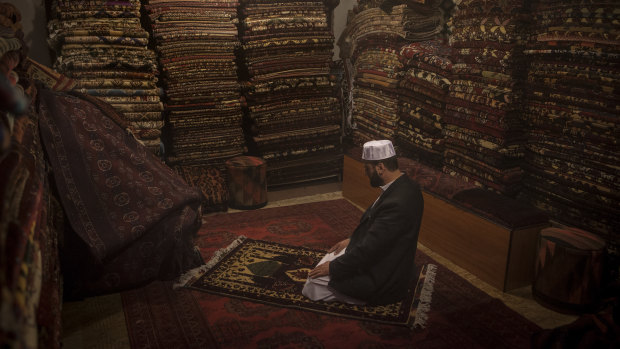 Noorullah Ahmadi prays at his shop, Handy Crafts Jewelers Store, on Chicken Street in Kabul.